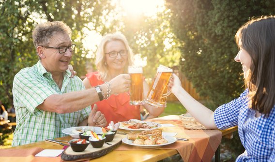 Bild: Zwei Frauen und ein Mann, die Zoigl trinken und eine Kleinigkeit Essen